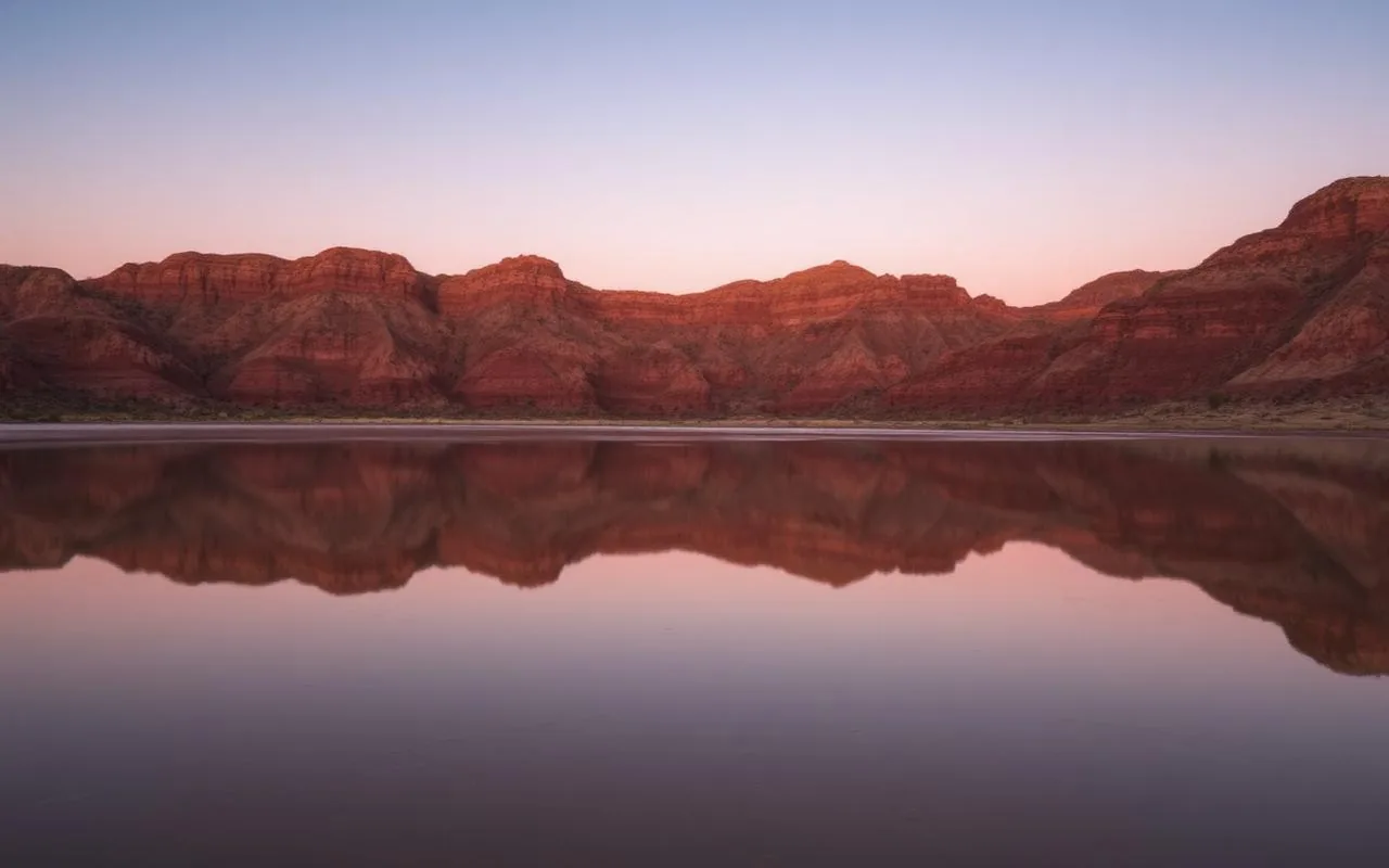 Quiet hidden Arizona desert lake at sunrise reflecting red mesas